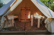 Entrance to Bell XL family tent lodge at Campsite Junora in France, showing cozy furniture inside.