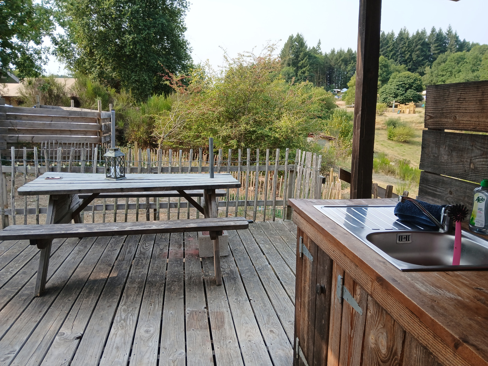 Houten terras met picknicktafel en buitenkeuken bij Bell XL family tent op Camping Junora in Frankrijk.