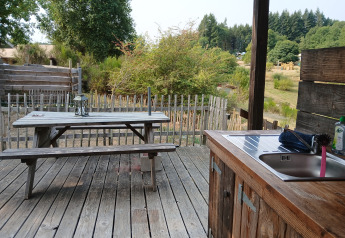 Wooden deck with picnic table and outdoor kitchen at Bell XL family tent lodge at Campsite Junora, France.