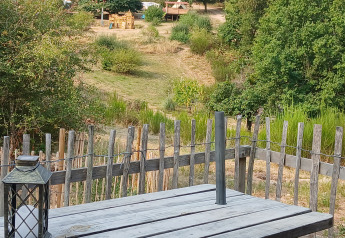 Vue depuis la tente Bell XL family au camping Junora, France, avec table en bois, lanterne et aire de jeux.