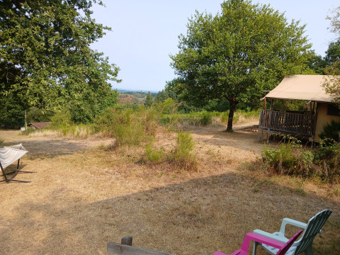 Uitzicht op een Bell XL familie tent lodge op Camping Junora in Frankrijk met bomen en stoelen.