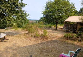 View of a Bell XL family tent lodge at Campsite Junora in France, with chairs, trees, and a hammock.