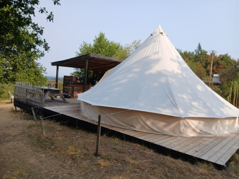 Bell XL family tent at Campsite Junora in France, featuring a wooden deck with a covered outdoor sitting area.