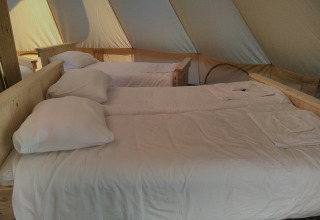 Intérieur d’une tente familiale Bell XL au Campsite Junora en France, avec trois lits faits et draps blancs.