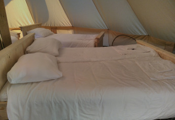 Inside Bell XL family tent at Campsite Junora, France, with three made-up beds and white linens.