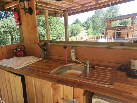 Gemütliche Holzküche mit Spüle, Teekessel und Utensilien im Bellzelt «6M» auf Campingplatz Junora, Frankreich.