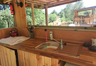 Udendørs køkken med træbordplade, vask, tepotte og køkkenredskaber på Bell tent «6M», Campsite Junora, Frankrig.