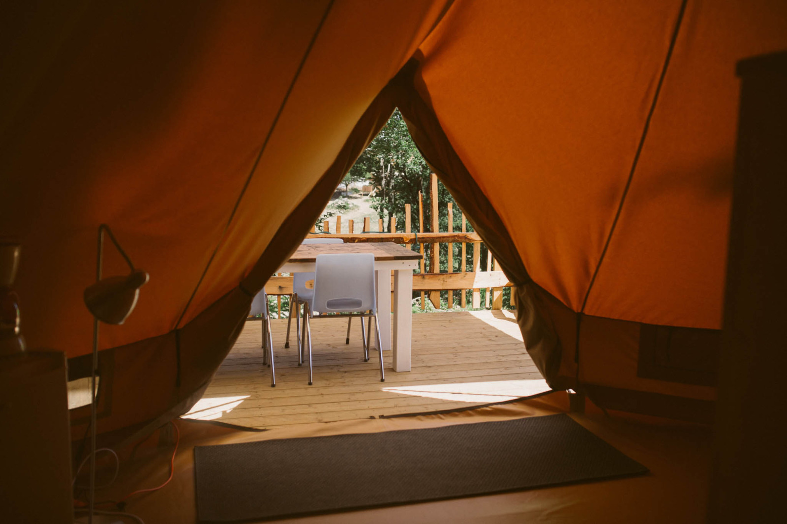 Uitzicht vanuit een Bell-tent op camping Junora in Frankrijk, met tafel en stoelen op houten terras.