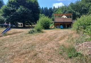 Vista della Bell tent «6M» al Campeggio Junora in Francia, prato verde, rifugio in legno e bambini che giocano.
