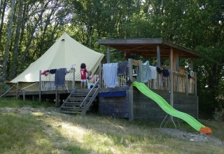Bell telt ved Campingplads Junora i Frankrig, med veranda, rutsjebane og børn, omgivet af frodig skov.