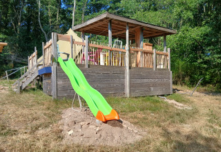 Scivolo verde accanto a terrazza in legno e tenda al campeggio Junora in Francia circondati dalla natura.