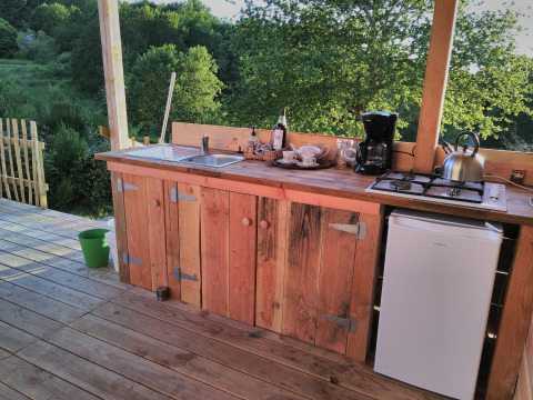 Outdoor wooden kitchen at Bell tent 6M, Campsite Junora, France, with countertop and nature view