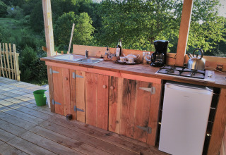 Outdoor wooden kitchen at Bell tent 6M, Campsite Junora, France, with countertop and nature view