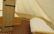 Interior of a Bell tent «6M» at Campsite Junora in France, featuring two single beds and wooden furniture.