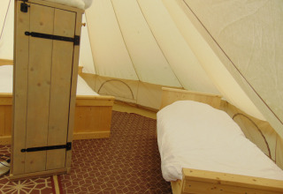 Indersiden af en Bell telt «6M» på Campsite Junora i Frankrig med to enkeltsenge og træmøbler.