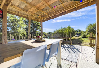 Udendørs spiseområde under trætag på Bell tent «6M» ved Campsite Junora i Frankrig med udsigt til natur.