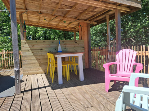 Overdekt terras met kleurrijke stoelen bij Bell tent «6M» op Camping Junora in Frankrijk.