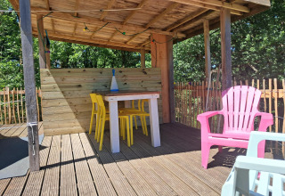 Zona salotto esterna coperta alla Bell tent «6M» presso il Campeggio Junora in Francia, con sedie colorate.