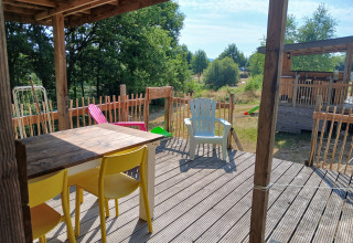 Terrasse en bois avec chaises colorées à la Bell tent 6M au Camping Junora en France, vue sur la nature.