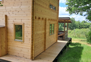Casa di legno chiamata Avignon al Campeggio Junora in Francia, circondata da verde e natura.
