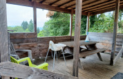 Covered wooden terrace with picnic bench and chairs at the 'Avignon' lodge at Campsite Junora, France.