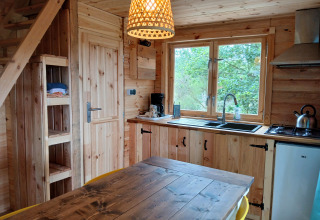 Houten interieur van de Avignon-lodge op Camping Junora in Frankrijk, met keuken en eethoek.