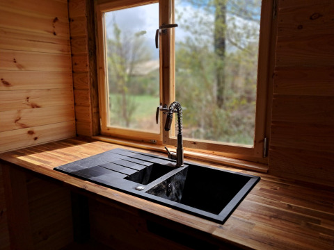 Moderne zwarte keukenkraan en spoelbak bij raam in houten lodge op Camping Junora, Avignon, Frankrijk.