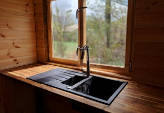 Moderne zwarte keukenkraan en spoelbak bij raam in houten lodge op Camping Junora, Avignon, Frankrijk.