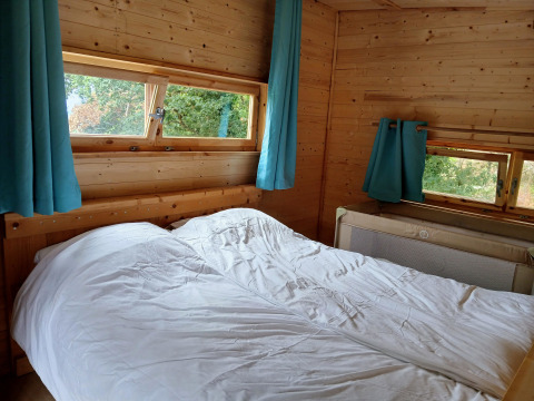 Camera da letto nella lodge Avignon al Campeggio Junora in Francia, letto matrimoniale e tende turchesi.