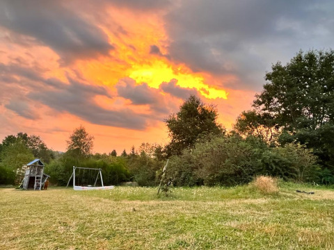 Parco giochi e altalene su prato al tramonto presso Emperor Bell Tent, Campsite Junora, Francia.