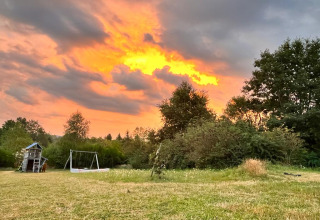 Speelplein en schommels op grasveld bij zonsondergang aan Emperor Bell Tent, Campsite Junora, Frankrijk.