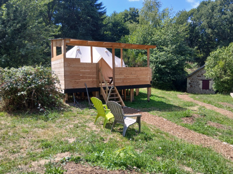 Houten terras met Emperor Bell Tent en stoelen, omgeven door natuur op Campsite Junora in Frankrijk.
