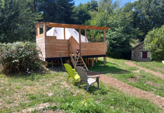 Houten terras met Emperor Bell Tent en stoelen, omgeven door natuur op Campsite Junora in Frankrijk.