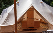Entrance to the luxurious Emperor Bell Tent at Campsite Junora in France, featuring wooden furniture inside.