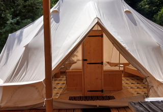 Ingresso della lussuosa Emperor Bell Tent al Campeggio Junora in Francia, con arredi in legno all'interno.