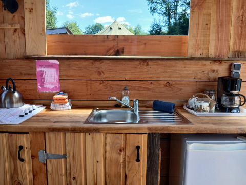 Sfeervolle keuken in Emperor Bell Tent, Campsite Junora, Frankrijk, met houten blad en keukengerei.