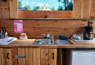 Accogliente cucina presso Emperor Bell Tent al Campeggio Junora, Francia, con piano in legno e utensili.
