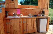Outdoor wooden kitchen setup with sink, kettle, fridge, and coffee maker at Emperor Bell Tent, France.