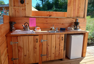 Cucina in legno all’aperto con lavello, bollitore, frigorifero e macchina da caffè all’Emperor Bell Tent, Francia.