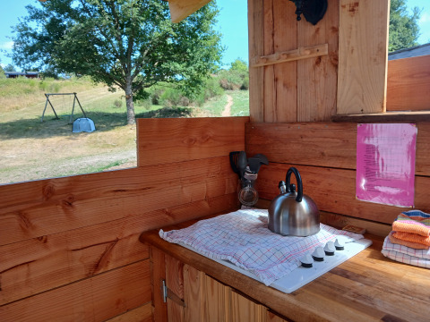 Buitenkeuken aan Emperor Bell Tent op Camping Junora in Frankrijk, met fornuis, ketel en uitzicht.