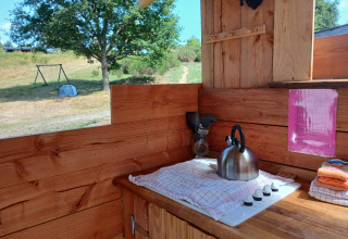 Cucina all’aperto presso Emperor Bell Tent al Campeggio Junora in Francia, con fornello e bollitore.
