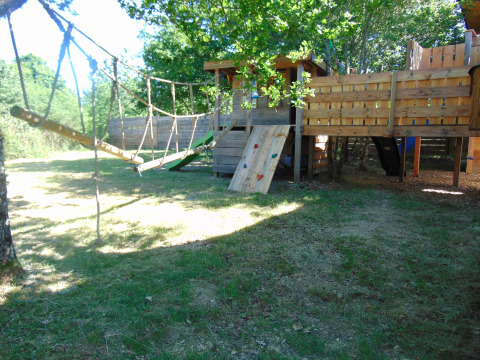 Buitenspeeltuin met boomhut, touwbrug en klimwand bij Eco-Chalet EXTRA op Camping Junora in Frankrijk.