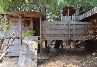 Kinderboomhut met klimwand bij Eco-Chalet EXTRA op Camping Junora in Frankrijk, omgeven door bomen.