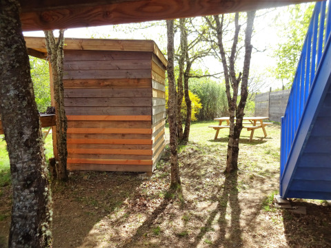 Foto van de Eco-Chalet EXTRA boomhut op Camping Junora in Frankrijk, met tafels en bomen.