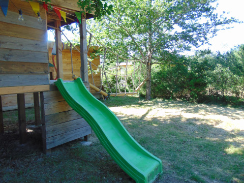 Casa sull’albero con scivolo verde e bandierine a Eco-Chalet EXTRA, Campeggio Junora, Francia.