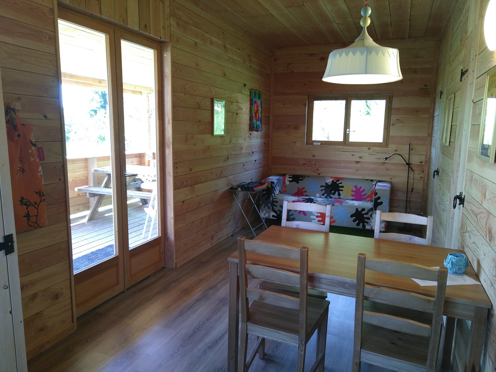 Interieur van Eco-Chalet EXTRA boomhut op Camping Junora, met houten wanden, tafel en bank.