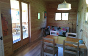 Interior of Eco-Chalet EXTRA treehouse at Campsite Junora, showing wooden walls, table, and sofa.