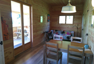 Interieur van Eco-Chalet EXTRA boomhut op Camping Junora, met houten wanden, tafel en bank.