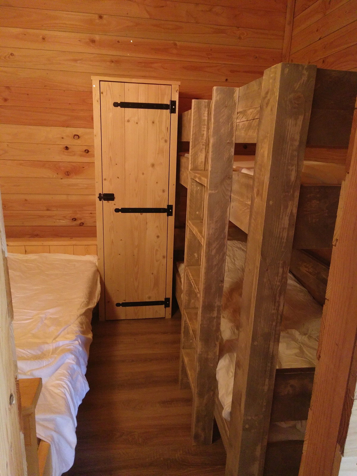 Knusse houten kamer in Eco-Chalet EXTRA, Camping Junora, Frankrijk, met tweepersoonsbed en stapelbed.