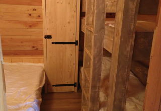 Accogliente stanza in legno dell’Eco-Chalet EXTRA al Campeggio Junora in Francia con letto e letti a castello.